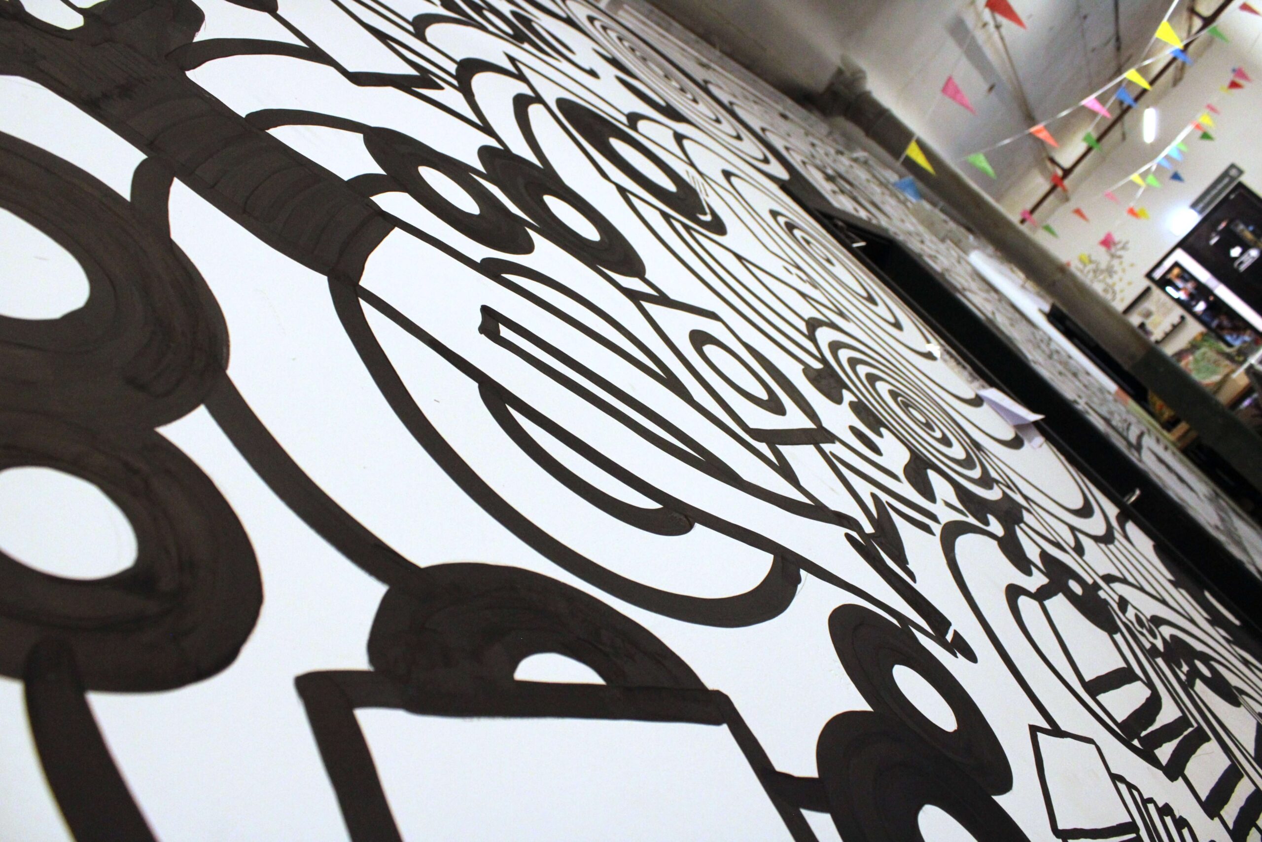 Large black and white mural artwork inside Leigh Spinners Mill featuring bold abstract patterns and industrial style interior details.