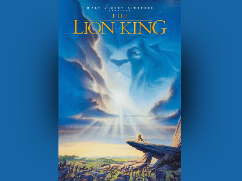 Poster for The Lion King featuring a dramatic savanna landscape beneath a glowing blue sky. At the top, a large translucent image of an adult lion’s face emerges from swirling clouds, watching over the scene with a powerful, regal expression. Bright beams of sunlight break through the clouds and shine downward onto a rocky outcrop. Near the edge of the outcrop, a small lion cub stands silhouetted against the light in a triumphant pose. Below, a wide gathering of animals stretches across the grasslands, all facing toward the rock formation. The composition creates an epic, majestic atmosphere emphasizing themes of destiny, leadership, and the circle of life.