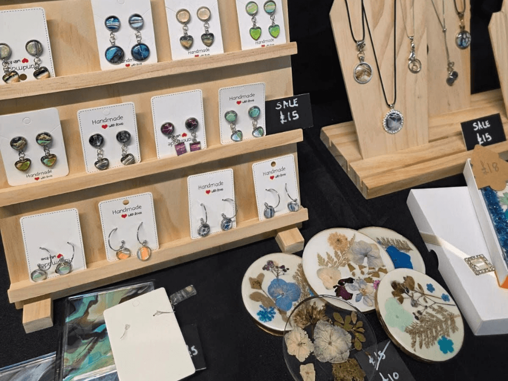 Handmade jewellery, resin coasters and artisan gifts displayed for sale at a makers market stall inside Leigh Spinners Mill.