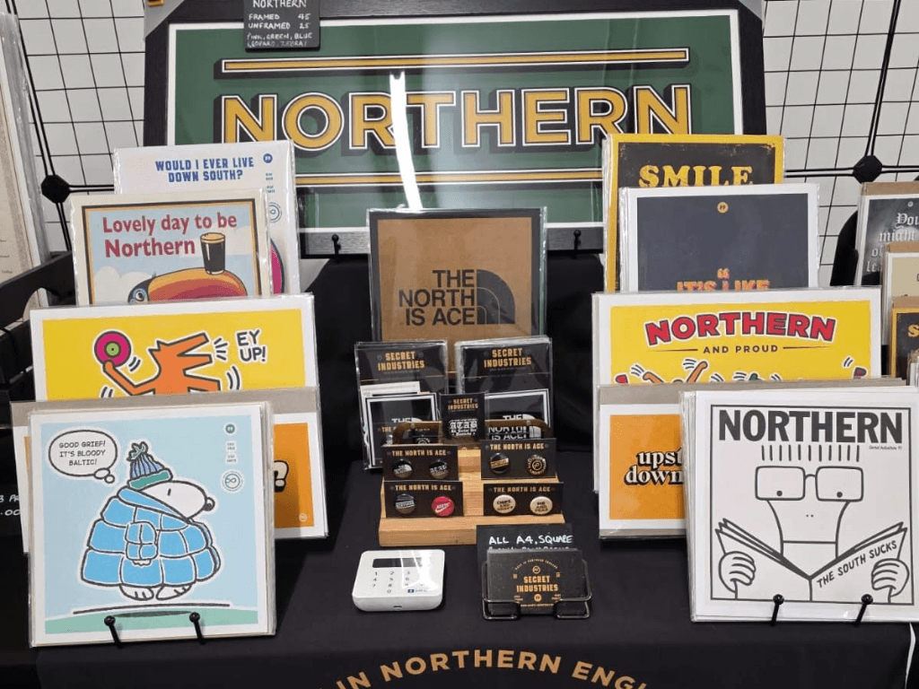Northern themed artwork, prints, badges and gifts displayed by an independent trader at a makers market in Leigh Spinners Mill.