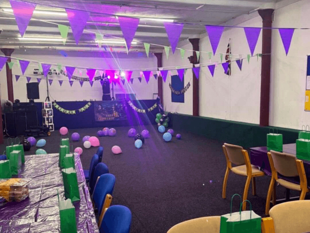 Community Room at Leigh Spinners Mill decorated for a children's party or community celebration, with bunting, balloons, tables and entertainment equipment set up for the event.