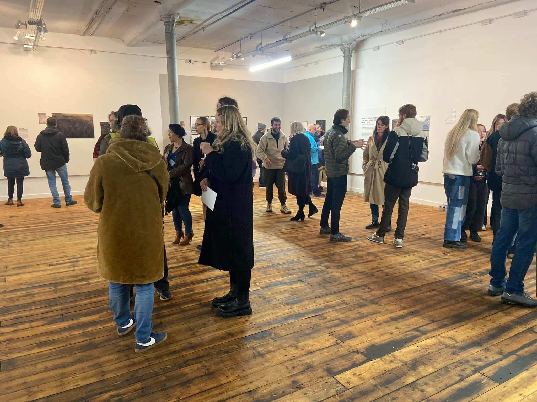 Visitors attending an exhibition in the Horrocks Gallery at Leigh Spinners Mill, viewing artwork and socialising within the flexible community event space.