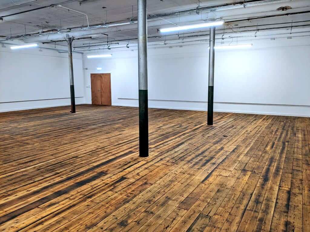 Horrocks Gallery at Leigh Spinners Mill featuring original wooden flooring, white walls and an open flexible event space suitable for exhibitions, meetings and community activities.