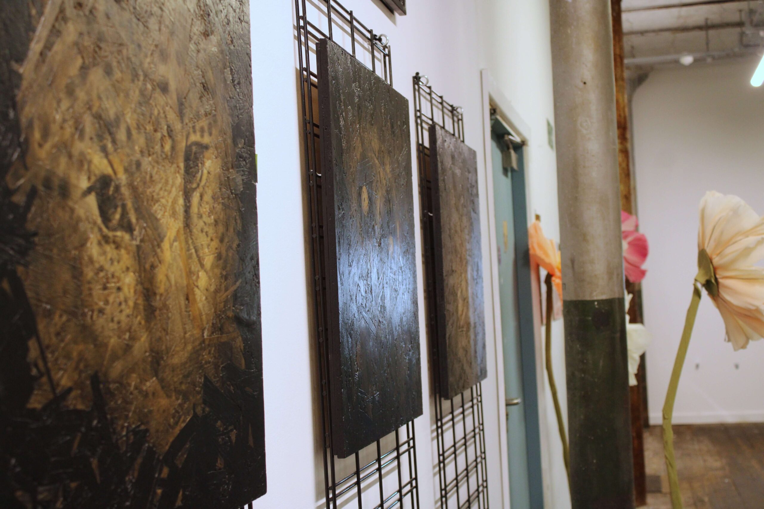 Contemporary artwork exhibited inside Spinners Mill, with paintings mounted along a corridor featuring original mill columns and wooden floors.
